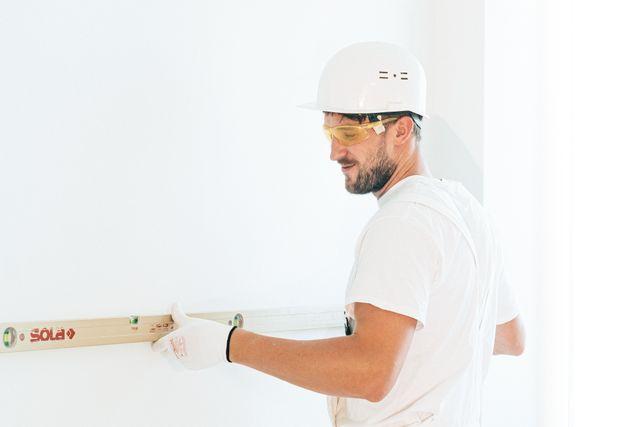 a person holding a level to a wall